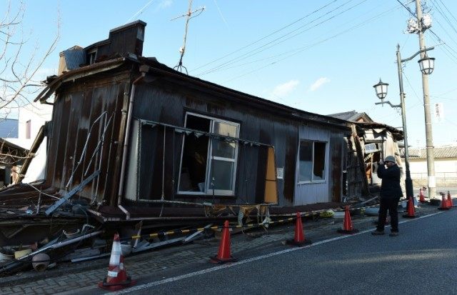 A visitor looks at an abandoned house in the ghost town of Namie, Japan's Fukushima Prefec