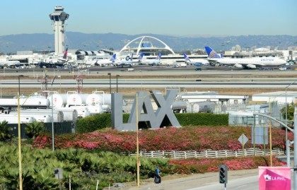 A traveller pulls his bags while walking past an LAX sign at Los Angeles International Air