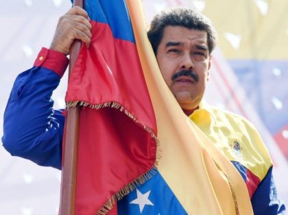 Venezuelan President Nicolas Maduro holds a flag during a demonstration against the United