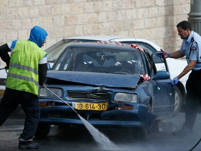 An Israeli policeman inspects a vehicle with its windshield riddled with bullet holes at t