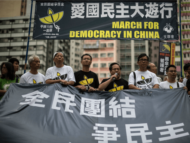 Pro-democracy protesters take turns to speak as they stand behind a huge banner in Hong Kong on May 31, 2015, before a rally to commemorate the 1989 crackdown at Tiananmen Square in Beijing, prior to the incident's 26th anniversary on June 4.