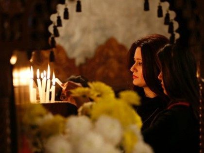 A Palestinian Christian woman lights a votive candle during Orthodox Christmas celebration