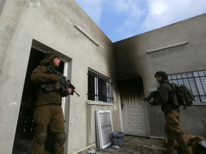 Israeli security forces stand guard outside a Palestinian burnt-out house belonging to a k