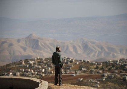 Jewish settler Refael Morris stands at an observation point overlooking the West Bank vill