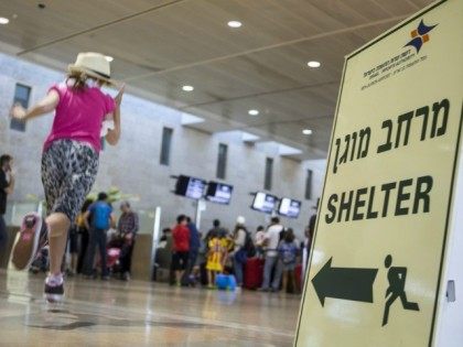 A girl runs past a sign directing passengers to a shelter at Ben Gurion International airport, near the Mediterranean Israeli coastal city of Tel Aviv on August 21, 2014, following a warning issued by Hamas's armed wing that they will target the airport from 6 am (0300 GMT) in a …
