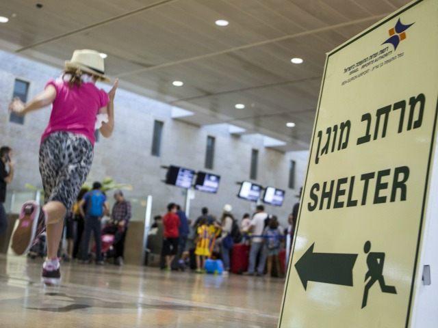 A girl runs past a sign directing passengers to a shelter at Ben Gurion International airp
