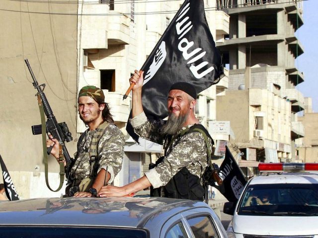 Militant Islamic State fighters wave flags as they take part in a military parade along the streets of Syria’s northern Raqqa province June 30, 2014. REUTERS/Stringer