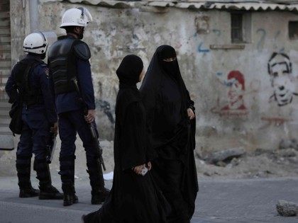 Bahraini women pass by riot police watching for protesters, to prevent a third day gathering of demonstrators against Saudi Arabia's execution of Shiite cleric Sheikh Nimr al-Nimr in Daih, Bahrain, a largely Shiite suburb of the capital, Monday, Jan. 4, 2016. Graffiti on the wall is of people killed in …