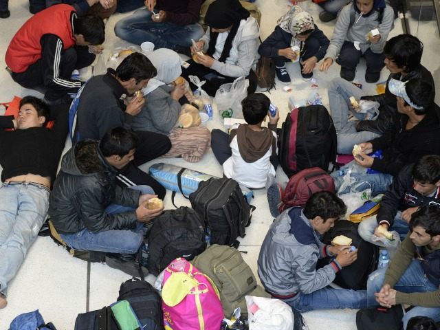 Refugees eat as they sit on the ground at the hall of the main train station in Salzburg,