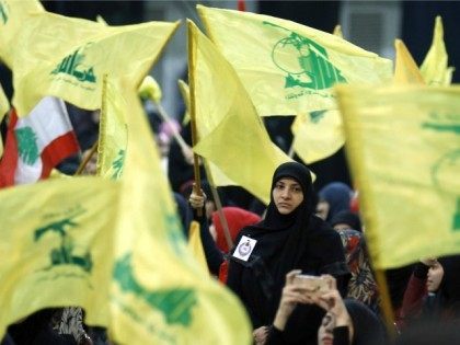 Supporters wave the flag of Lebanon's Shiite movement Hezbollah as they watch the movement's leader Hassan Nasrallah give a televised speech from an undisclosed location during a rally held in the southern suburbs of Beirut on February 16, 2016