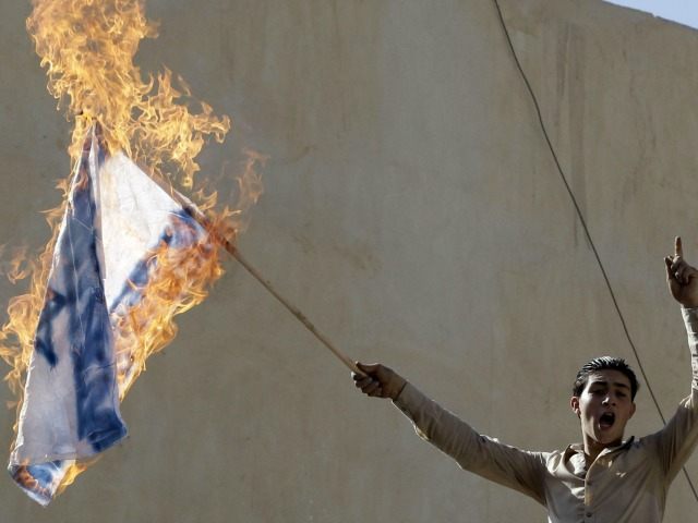 A Jordanian protester holds a burning Israeli flag during a demonstration near the Israeli Embassy in the capital Amman in solidarity with the Palestinians on October 16, 2015.