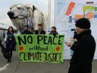 greenpeace Activists hold a banner reading 'No peace without climate justice' in front of a giant polar beer puppet called Aurora by environmental organization Greenpeace during a demonstration at the venue of the COP21 United Nations climate change conference in Le Bourget, on the outskirts of Paris, on December 11, 2015.