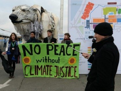 Activists hold a banner reading 'No peace without climate justice' in front of a giant pol