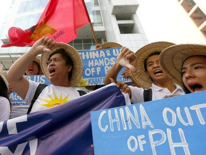 Protesters flash thumbs-down signs as they shout slogans during a rally near the Chinese C