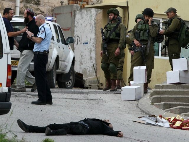 Israeli soldiers and police surround the body of one of two Palestinians who were killed a