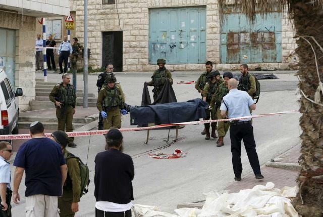 Israeli soldiers carry the dead body of one of two Palestinians, whom the Israeli military