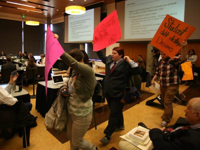Students walk out of a University of Oregon Board of Trustees meeting in Eugene, Ore., Fri