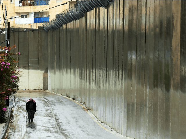 A Muslim man walks by the 'separation barrier' or 'security fence' in