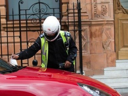 A traffic warden gives a parking ticket to a United Arab Emirates-registered Porsche Cayen