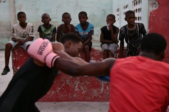 Children look on as Djaul, 25, a Haitian amateur, trains with another boxer in a courtyard