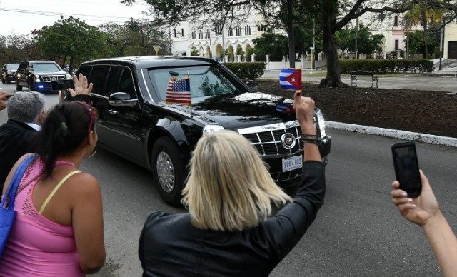 Cubans wave and take pictures as US President Barack Obama's car passes by on its way to R