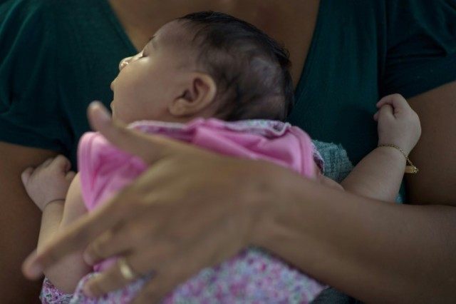 A mother holds her baby-daughter suffering from microcephaly, caught through an Aedes aegy