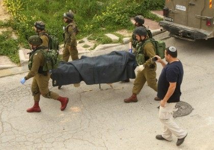 Israeli soldiers remove the body of a Palestinian assailant who was allegedly shot in head