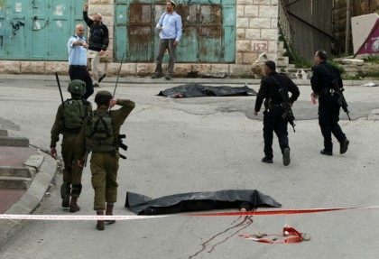 Israeli soldiers and police surround the bodies of two Palestinians who were killed in the West Bank town of Hebron, on March 24, 2016