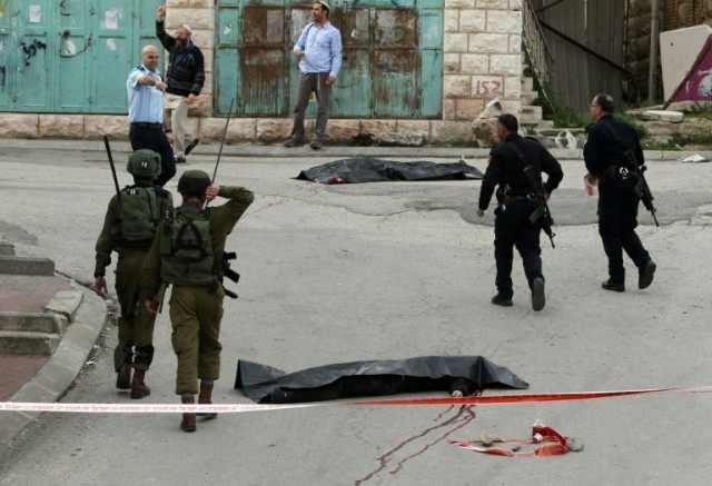 Israeli soldiers and police surround the bodies of two Palestinians who were killed in the West Bank town of Hebron, on March 24, 2016