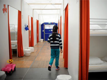 A girl walks in a corridor of a temporary holding centre for asylum seekers in a huge tent