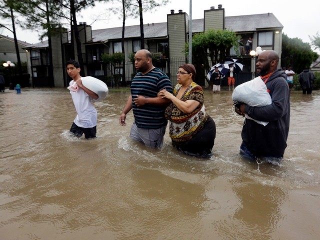 Darius Simon, second from left, helps his mother Carol, evacuate her flooded apartment com