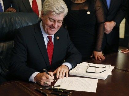 Mississippi Gov. Phil Bryant laughs at a joke while he signs HB1, a special session economic package of hundreds of millions of dollars of state money and incentives for a tire plant in western Hinds County and a shipyard in Gulfport, Monday, Feb. 8, 2016 at the Capitol in Jackson, …
