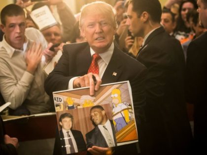 Republican presidential candidate Donald Trump holds depictions of himself on, "The Simpsons" and a photo with boxer Mike Tyson, given to him by an attendee during a campaign stop at the Radisson Hotel, Friday, Jan. 29, 2016, in Nashua, N.H.