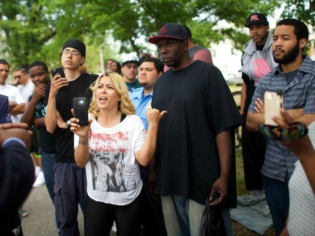 Neighborhood residents speak with a police officer about police mistreatment across the st