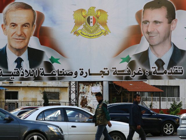 A billboard sponsored by Latakia's chamber of commerce and industry shows pictures of Syrian President Bashar al-Assad (R) and his late father former president Hafez al-Assad in the coastal city of Latakia, the provincial capital of the heartland of Syrian president's Alawite sect, on March 17, 2016. / AFP / …