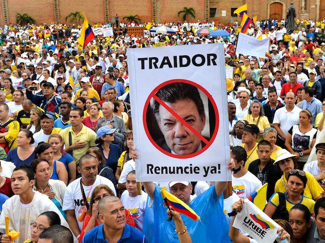 People hold a banner with the picture of Colombian President Juan Manuel Santos reading "Traitor. Resign now" as they take part in the "No More" march against his government and the Revolutionary Armed Forces of Colombia (FARC) guerrillas in Cali, department of Valle del Cauca, Colombia, on April 2, 2016. …
