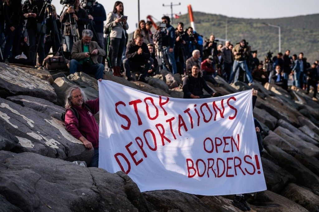 TOPSHOT - German activists show a banner during the arrival of a small Turkish ferry carrying migrants who are deported to Turkey on April 4, 2016 at the port of Dikili district in Izmir. Migrants return from Greece to Turkey begun under the terms of an EU deal that has worried aid groups, as Athens struggles to manage the overload of desperate people on its soil. Over 51,000 refugees and migrants seeking to reach northern Europe are stuck in Greece, after Balkan states sealed their borders. Hundreds more continue to land on the Greek islands every day despite the EU deal. / AFP / OZAN KOSE (Photo credit should read OZAN KOSE/AFP/Getty Images)