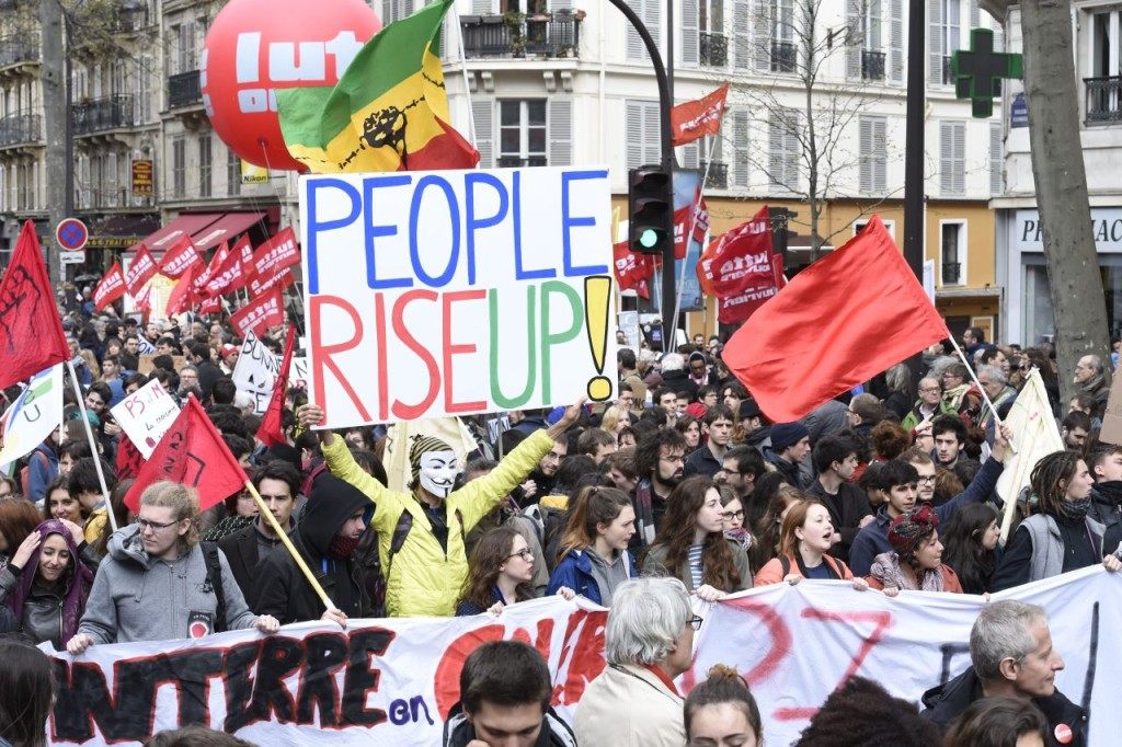 Protester Jean-Baptiste Redde aka Voltuan (C) holds up a placard reading "People rise up !" (MIGUEL MEDINA/AFP/Getty Images)