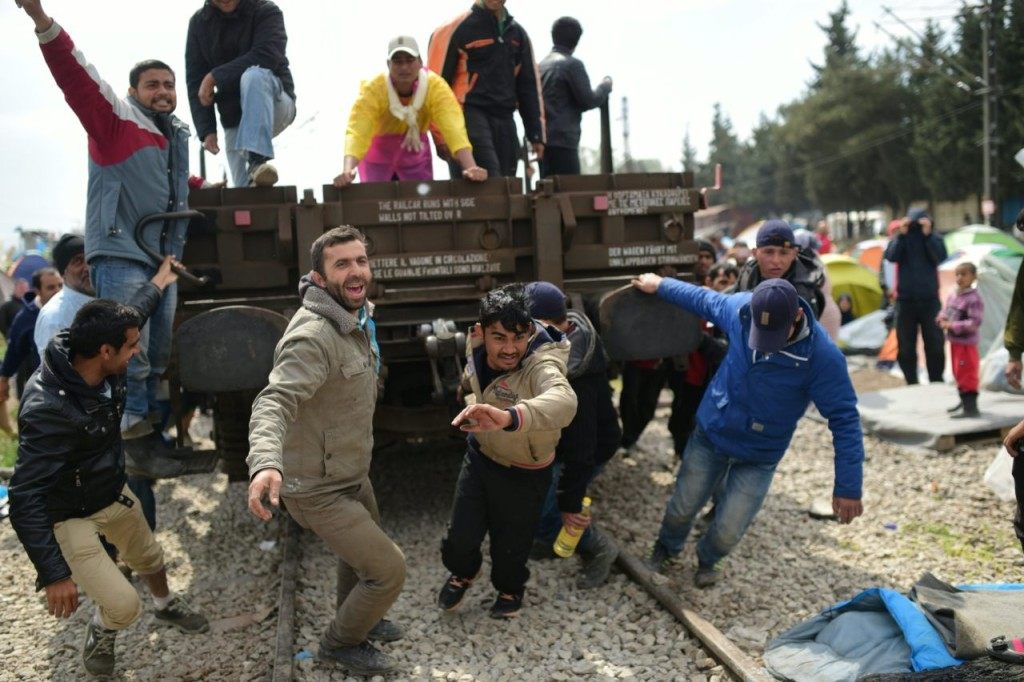 TOPSHOT - Refugees and migrants pull a wagon in an attempt to go through a barricade held by Greek police as they protest to call for the reopening of the border near their makeshift camp in the northern border village of Idomeni, on April 11, 2016. A plan to send back migrants from Greece to Turkey sparked demonstrations by local residents in both countries days before the deal brokered by the European Union is set to be implemented. / AFP / BULENT KILIC (Photo credit should read BULENT KILIC/AFP/Getty Images)