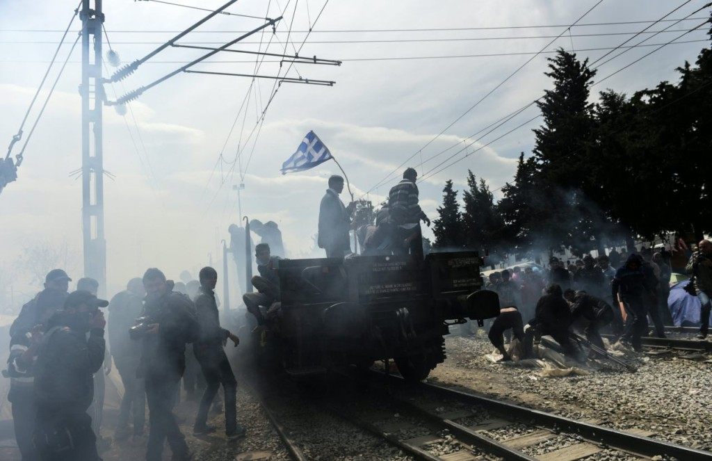 Refugees and migrants protest as a unexploded gas canister explodes mistakenly near by as they rally demanding the reopening of the border near their makeshift camp in the northern Greek border village of Idomeni, on April 11, 2016. Fresh protests broke out as Greece and Macedonia blamed each other for an incident in which tear gas and rubber bullets were fired on migrants trying to breach the closed border to get to western Europe on April 10. Medical charity Doctors Without Borders (MSF) said 260 people were treated for injuries after the flare-up on the Greece-Macedonia border. / AFP / BULENT KILIC (Photo credit should read BULENT KILIC/AFP/Getty Images)