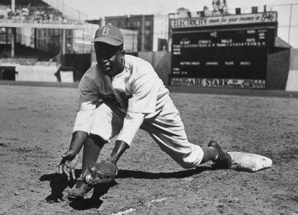 American baseball player Jackie Robinson (1919 - 1972) grounds a ball at first place while