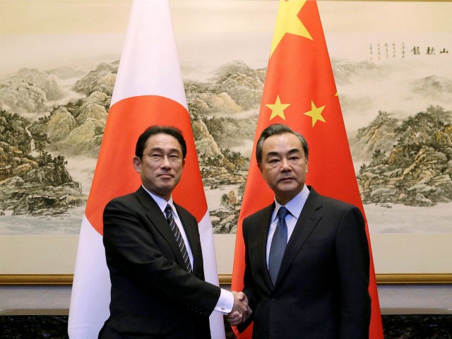Japanese Foreign Minister Fumio Kishida (L) shakes hands with China's Foreign Minister Wan