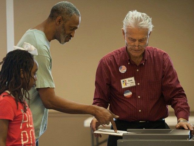 An election worker helps a voter to process his paper ballot during Missouri primary votin