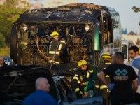 Israeli firemen and emergency services check the remains of a burnt-out bus after extinguishing the flames following an explosion in Jerusalem on April 18, 2016.