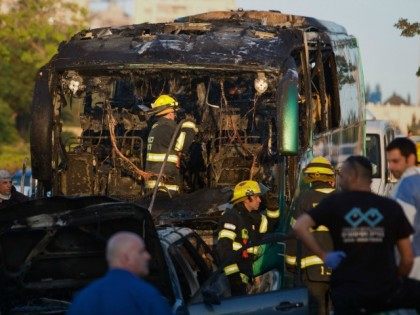Israeli firemen and emergency services check the remains of a burnt-out bus after extingui