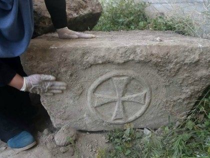 Palestinian archaeologist Hyam al-Betar looks at a foundation stone bearing a Greek Christ