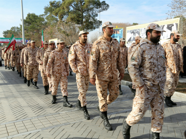 Iranian soldiers walk past giant boards displaying pictures of the late founder of the Isl