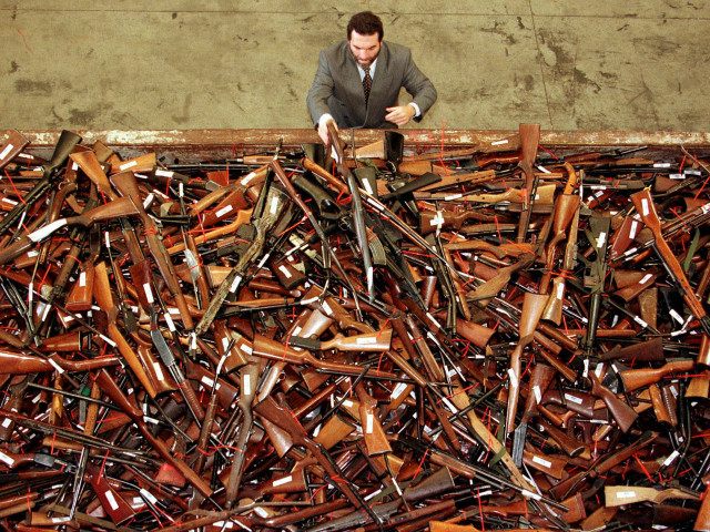 Mick Roelandts, firearms reform project manager for the New South Wales Police, looks at a pile of about 4,500 prohibited firearms in Sydney that have been handed in over the past month under the Australian government's buy-back scheme July 28. REUTERS/DAVID GRAY