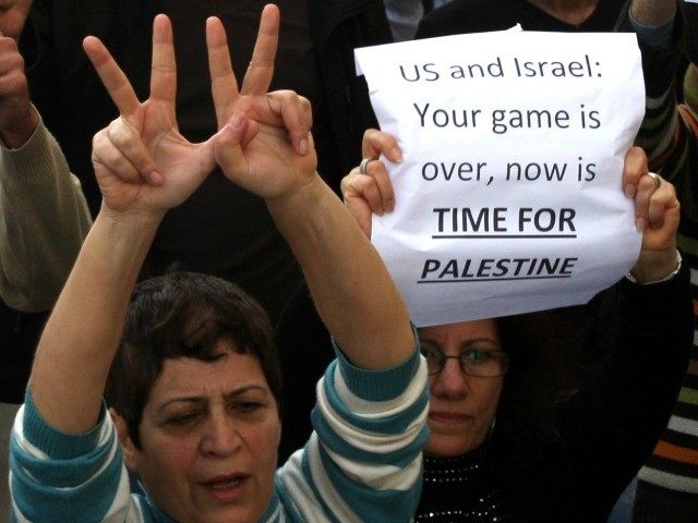 Palestinians hold signs as they rally in the centre of the West Bank city of Ramallah dema
