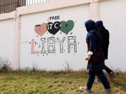 LIBYA, Tripoli : Students walk past a wall painted with a graffiti reading "free Libya" in the Libyan capital Tripoli, on March 31, 2016. / AFP / MAHMUD TURKIA